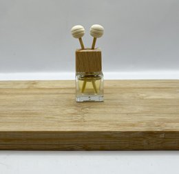 Small glass bottle with gold cap and two white atomizer sprayers, placed on a wooden surface.