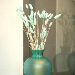Dried flower bouquet in a light blue vase with white and blue accents.
