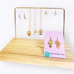 Copper and wood jewelry display rack with hanging necklaces and earrings.