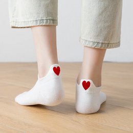 Cozy white socks with red heart designs, perfect for casual wear.