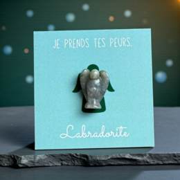  A greeting card with a rose quartz angel figurine and a pink heart design. The card is enclosed in a soft, cream-colored drawstring bag with a pink heart motif.
