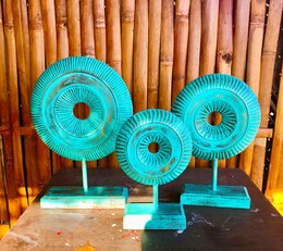 Turquoise decorative sculptures made of woven material, displayed on a wooden background.