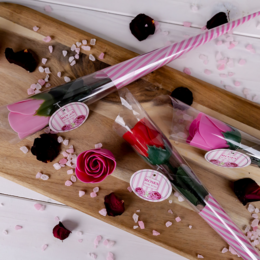 A set of rose-shaped bath soaps in various shades of pink and red, presented in a decorative gift box with floral patterns.