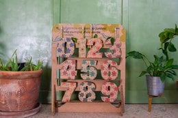Wooden pencil holder with floral design, available in multiple languages.