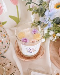 "Floral scented candle with dried flowers, pink and purple petals, glass jar, botanical design, decorative"