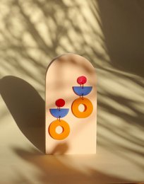 Vibrant statement earrings featuring bold geometric shapes in red, blue, and orange.