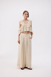  Beige linen blouse with ruffled details and wide-leg pants in a matching neutral tone.
