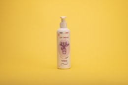 A 250ml bottle of Cuddle Body Milk for kids, featuring a white bottle with a pink and purple label.