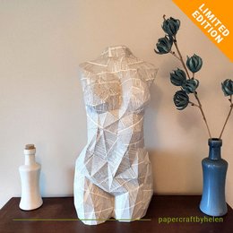 A DIY Venus van Dale craft kit featuring a geometric, abstract sculpture made of white paper. The sculpture is 80 cm tall and 41 cm wide, with a polygonal, faceted design.
