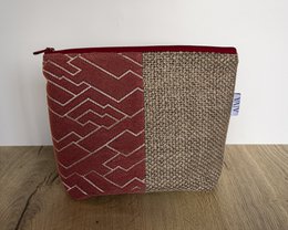 A red and beige toiletry bag with a geometric pattern and a zipper closure.