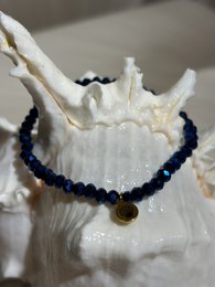 Small black beaded bracelet with a gold charm.