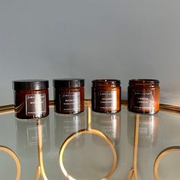 Amber-colored scented candle in a 60ml glass jar. Offers a variety of fragrance options including Magnolia & Honeysuckle, Coco & Vanilla, Tobacco & Vanilla, and more.