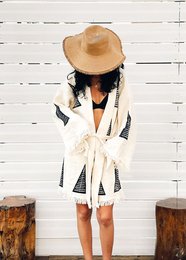 Organic cotton short kaftan with geometric print, featuring a loose, flowing silhouette and a wide-brimmed sun hat.