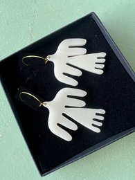 White dove-shaped earrings with black background. Delicate, minimalist design suitable for children.