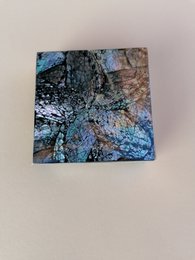 Square coasters with an abstract, colorful design featuring shades of blue, green, and brown.
