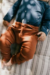 Gala baby pant in Mars red ribbed fabric, available in sizes 0-3, 3-6, 6-12, and 12-18 months, in the Terracotta color.
