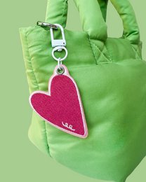 Bright green quilted bag with pink heart-shaped charm keyring attachment, modern minimalist design.