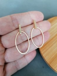 Gold-toned statement earrings with oval-shaped hoops.
