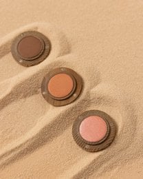 Powder blush in shades of Rosa, Tierra, and Melocotón, with a round, compact design and wooden packaging.