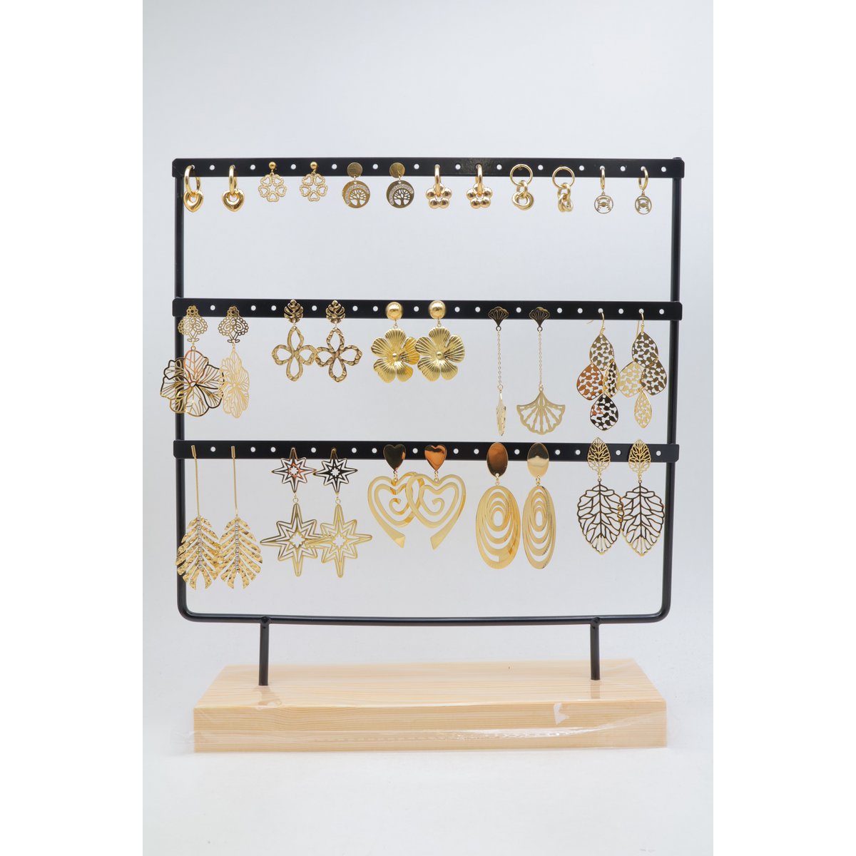 Lot de 16 paires de boucles d'oreilles assorties en acier inoxydable, présentées sur un présentoir métallique avec socle en bois.