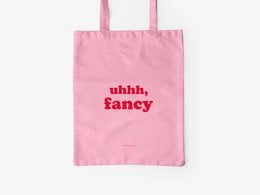 A pink cotton tote bag with the text "uhhh, fancy" printed in red on the front.