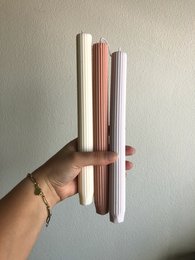 Tall, cylindrical ribbed dinner candles available in pink, lavender, white, olive, and grey colors.