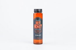 Ultra hot honey sauce in a glass bottle with a red label. Honey-based hot sauce with a spicy kick.