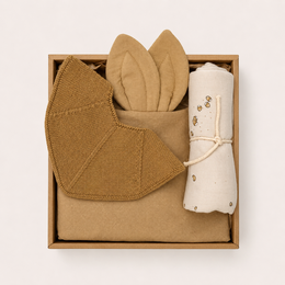A cozy gift box set containing a soft, plush stuffed animal in shades of green and gray, along with a coordinating blanket or towel.
