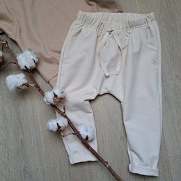 'Loose fit joggers in raw ecru color, made for kids. Features an elastic waistband and drawstring for adjustable fit. Suitable for casual everyday wear.'