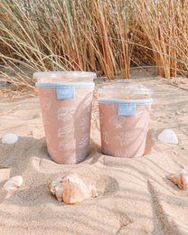 Beach-themed iced coffee sleeve, translucent pink, blue label, reusable cup holder, outdoor aesthetic.
