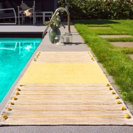A rectangular yoga rug in a yellow-olive color, made of natural materials, suitable for indoor or outdoor use near a swimming pool.