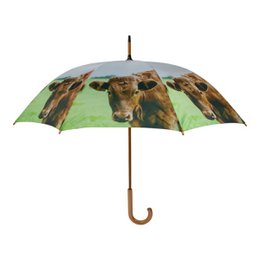 Large green and brown umbrella with a print of cows in a field.