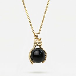 A gold necklace with a black onyx pendant. The necklace features a delicate chain and a decorative clasp. The onyx pendant is round in shape and has a smooth, polished surface.