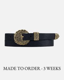 Skinny leather belt with a statement buckle in black, brown, and cognac colors. Available in sizes XS-XL. Features a cross-shaped buckle with an ornate design.