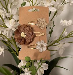  Set of 76 assorted hair clips featuring floral designs in various colors and materials, including metal, fabric, and rhinestones, suitable for kids' hairstyles.