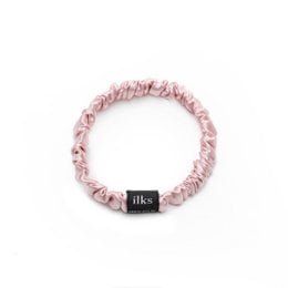 Small pink silk scrunchie with a black logo tag.