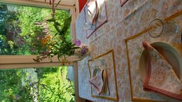 A small, rectangular tablecloth with a floral pattern in pink and ochre colors. The tablecloth has a delicate, embroidered design featuring flowers and leaves.