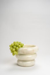 White marble decorative bowl with green grapes.