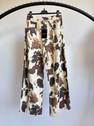 Beige wide-leg pants with brown and black cow print pattern, animal print design.