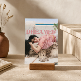 "Dreamer postcard featuring a woman in a pink dress embracing a dog. Vintage-style postcard with text 'Dreamer'."