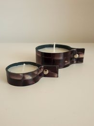 Leather tea light holder in a round, dark brown shape with metal accents.