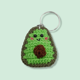 Cute crocheted avocado keychain with a smiling face and brown pit detail.