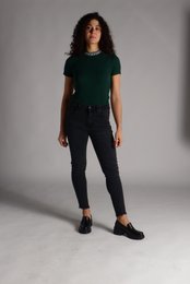 Slim-fit green top with short sleeves, black skinny jeans, and black shoes.