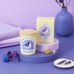 A round, tall lavender-scented candle in a blue glass container with a wooden lid. The candle is labeled "Sweet Dreams Aromatherapy Candle" and is available in small and medium sizes.