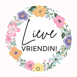 A round, glass tealight candle holder with the text "Lieve Vrienden" (Dear Friends) printed on it, surrounded by floral illustrations. The candle holder is placed next to a wrapped gift box.