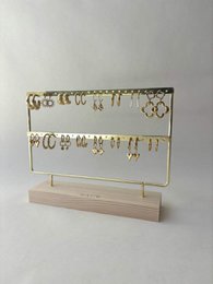Gold metal jewelry display stand with wooden base, earring organizer, minimalist design.