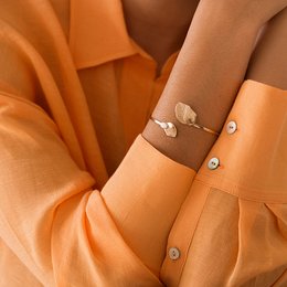 Sleek, minimalist bangle bracelet in a variety of neutral colors including amber, moss, midnight blue, coral, and more. Features a simple leaf-shaped design for a modern, elegant look.