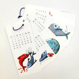 A 2024 wall calendar featuring the evolution of fish, with colorful illustrations of various fish species and marine life. The calendar pages display the months and dates in a simple, minimalist design.