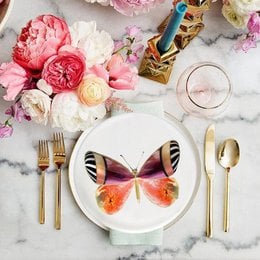 Elegant dessert plates with a butterfly motif, featuring a colorful butterfly design and coordinating tableware. The plates are part of the "La dolce vita di una farfalla" (The sweet life of a butterfly) collection, suitable for serving desserts or other sweet treats.