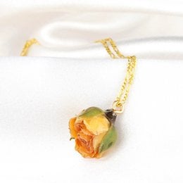 A saffron yellow rose pendant on a 925 sterling silver chain. The pendant features a real preserved rose encased in a glass dome, creating a unique and elegant piece of jewelry.